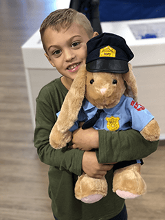 Child Hugging Stuffed Bunny in Police Uniform