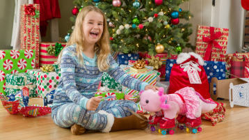 Child in front of Christmas tree playing with Build-A-Bear axolotl plush
