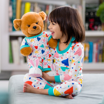 Build A Bear Matching Family Pajamas Promotion Up to 30% off. Photo of child holding Build A Bear while wearing matching Pajamas