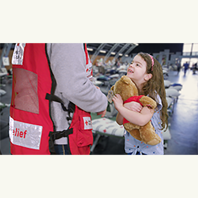 Red Cross worker handing a child a plush